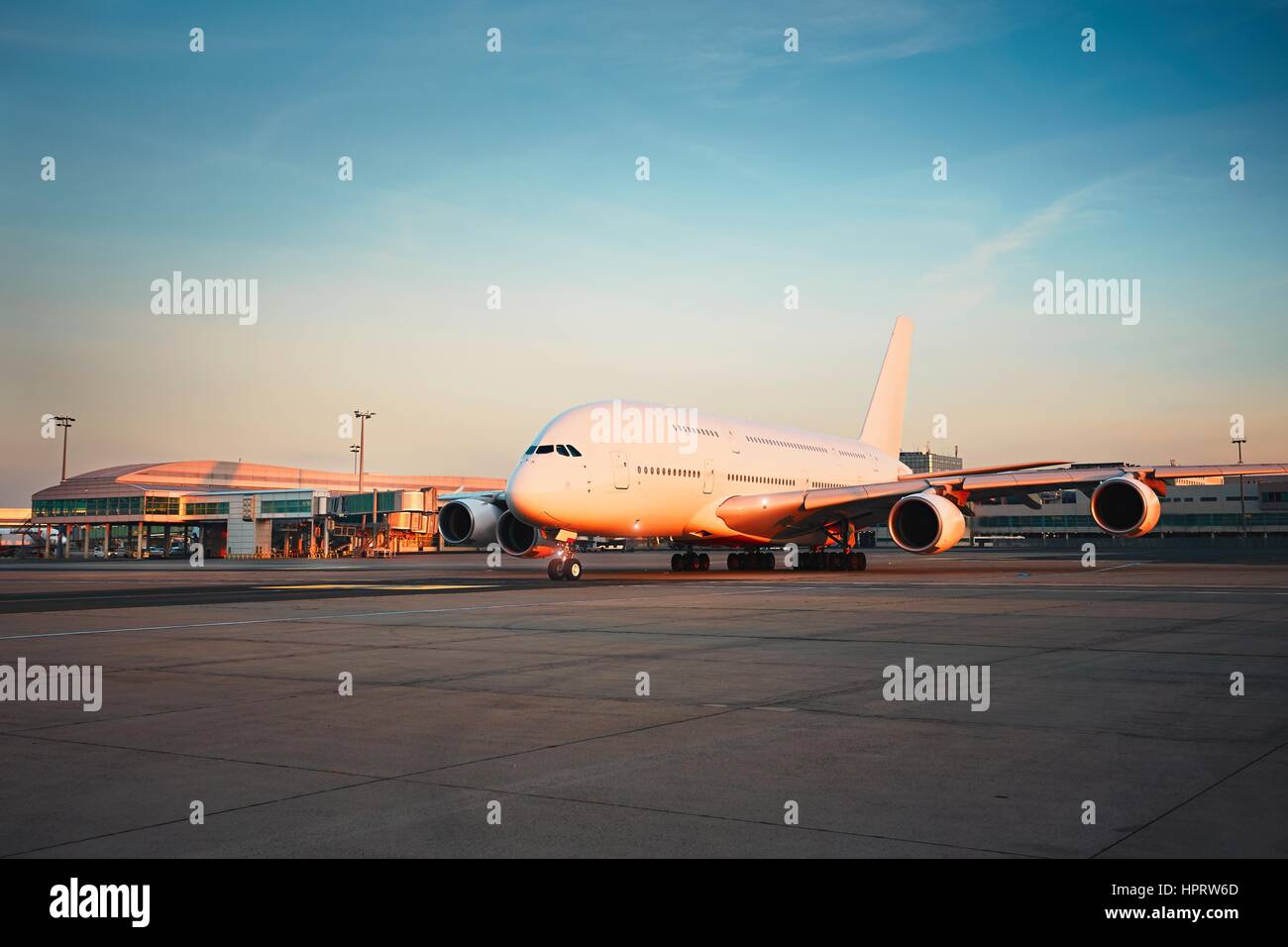Traffic of the airport at the sunset. Huge airplane is taxiing to the runway. Stock Photo