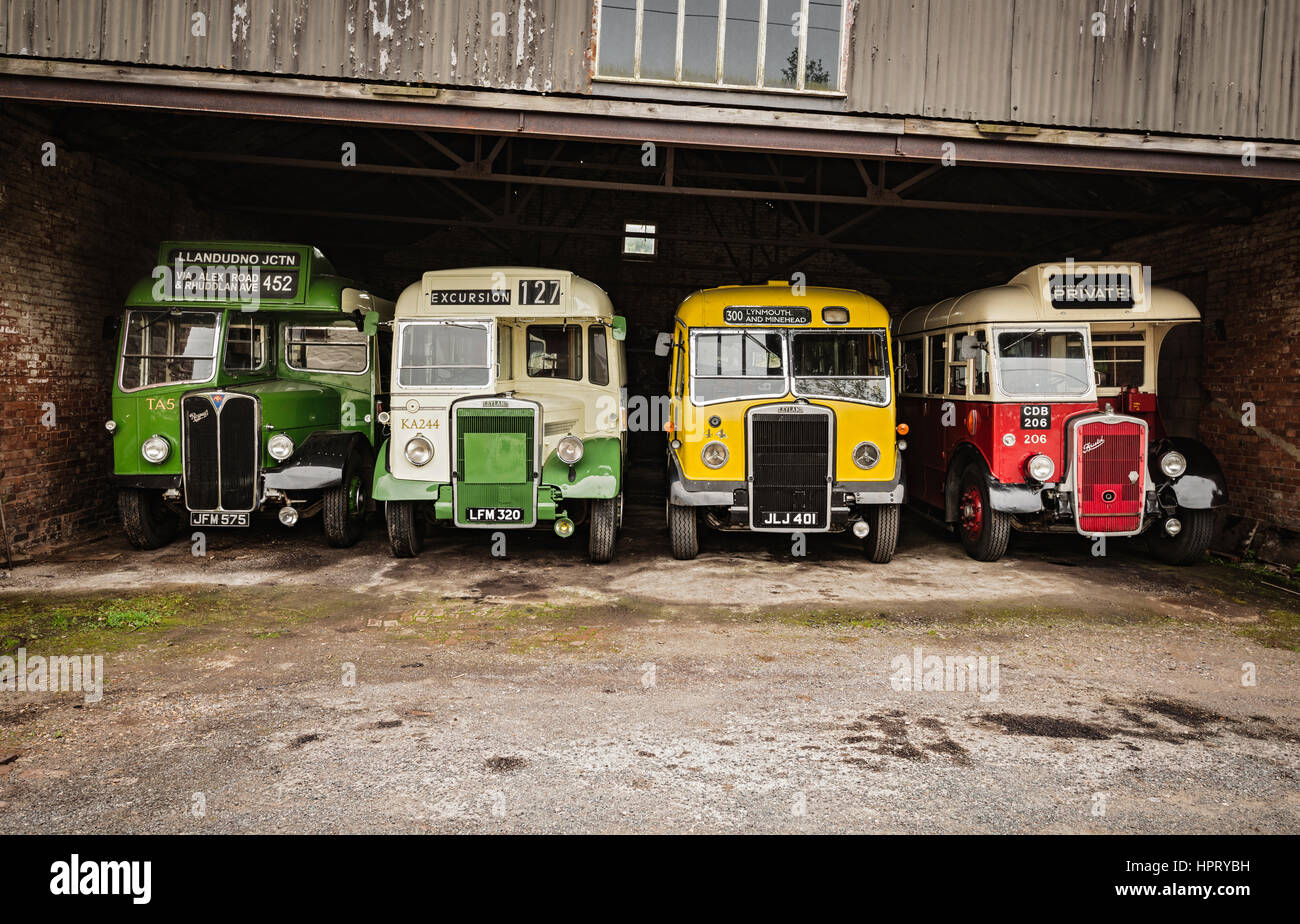 Four vintage buses parked inside a garage Stock Photo