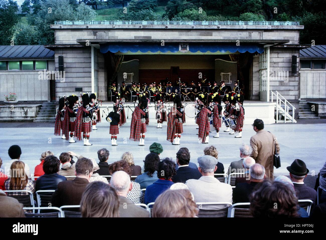 A group of bagpipe players stand in a circle and perform, other musicians are seated on the stage, 1965. Stock Photo