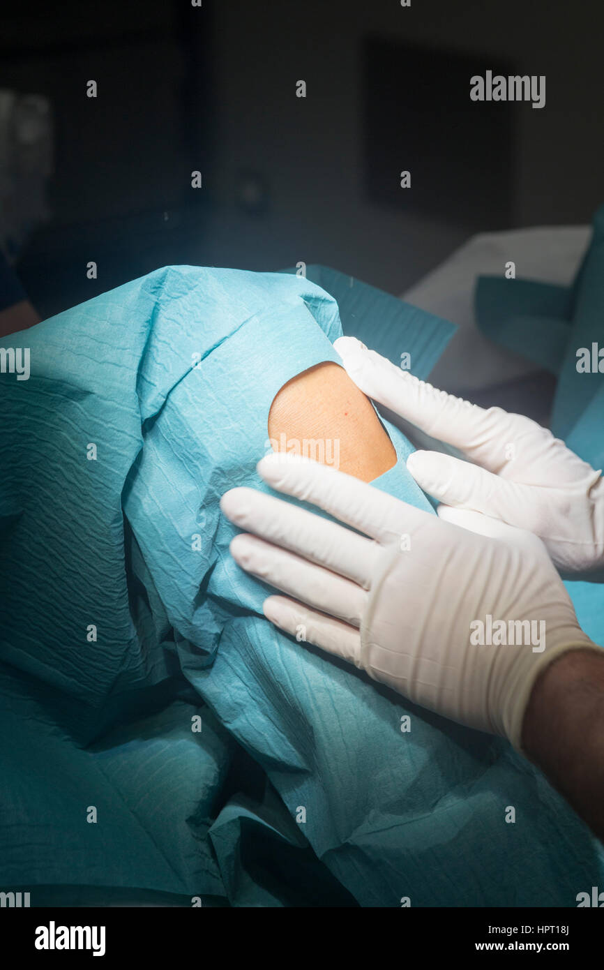 Preparing knee for surgery hospital operation medical procedure in emergency room operating theater. Stock Photo
