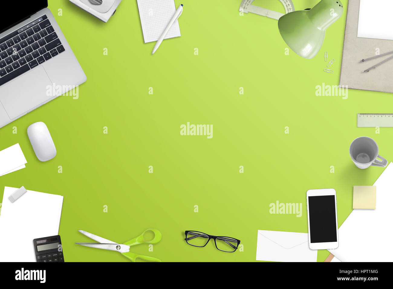 Mess on office desk with free space for text. Laptop computer, smart phone and office work accessories. Top view of green work space. Stock Photo