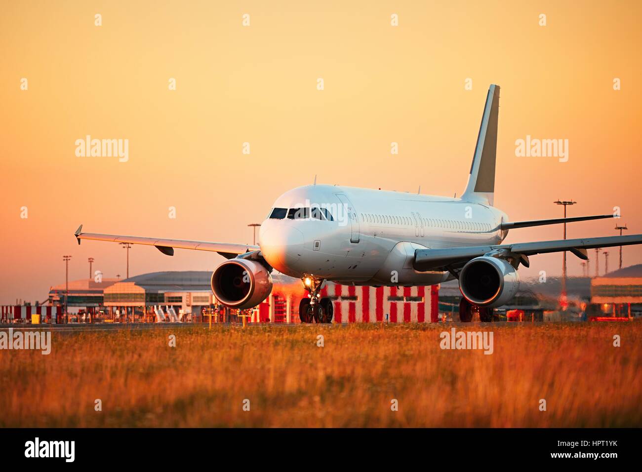 Airport at the sunset light. Airplane is taxiing to the runway for take off. Stock Photo