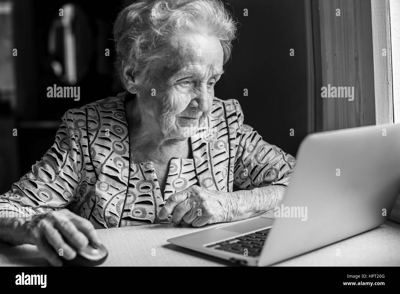 An elderly woman with a laptop. Black-and-white photo. Stock Photo