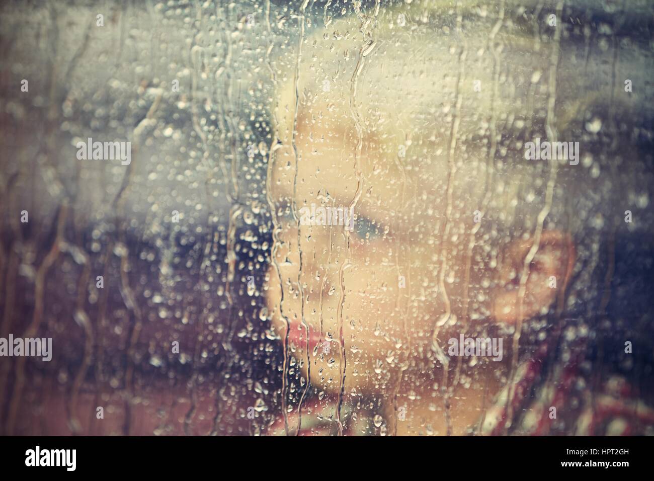 Little boy behind the window in the rain - selective focus Stock Photo