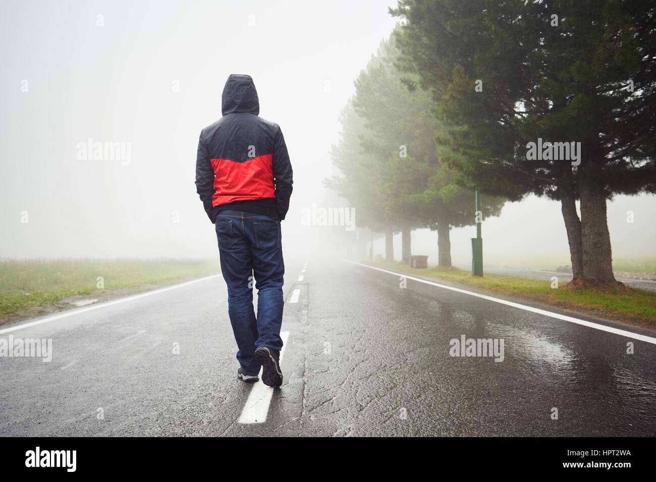 Lonely man is walking in mysterious fog Stock Photo