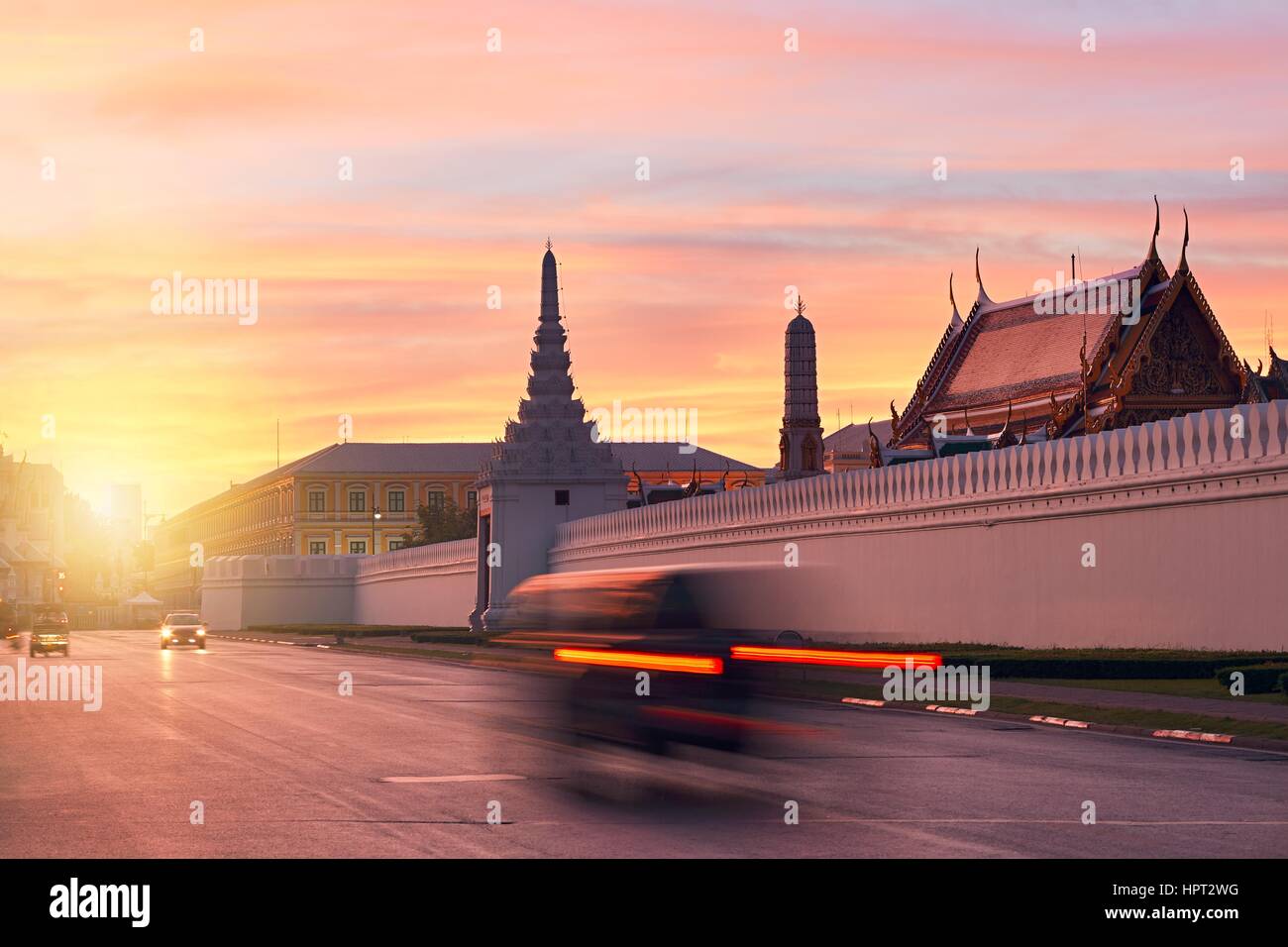 Tuk Tuk taxi in blurred motion in front of Grand Palace during beautiful sunrise  Bangkok, Thailand Stock Photo