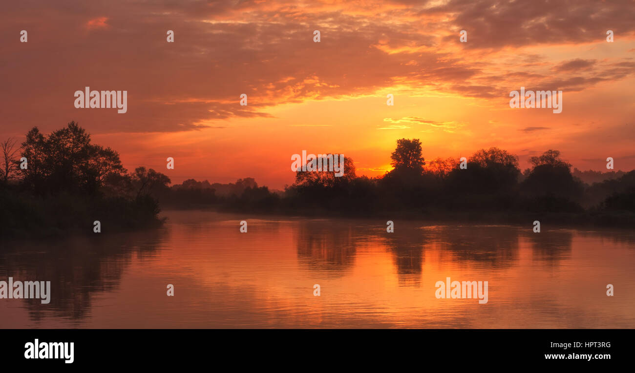Beautiful orange sunrise on lake with reflection Stock Photo