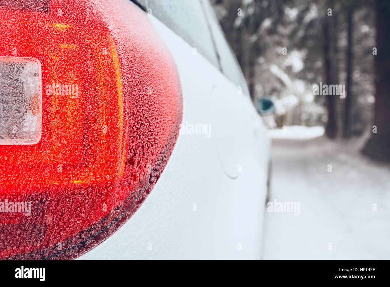 Detail of the stop light. White car on winter road. Stock Photo