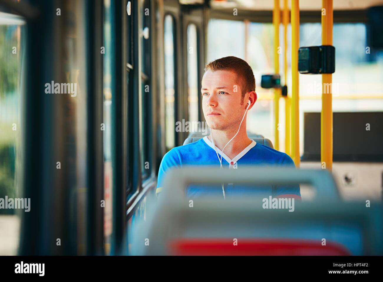 Loneliness man is wearing headphones and listening to music. Everyday life and commuting to work by public transportation. Handsome young man is trave Stock Photo