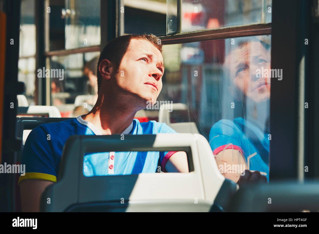 Everyday life and commuting to work by public transportation. Handsome young man is traveling by tram (bus). Stock Photo