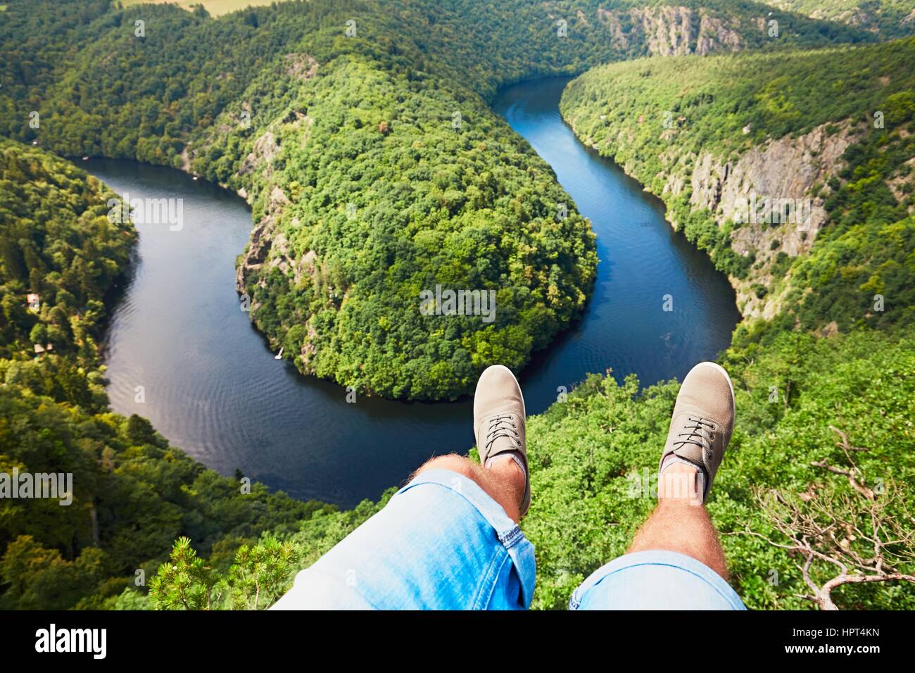Feet of the young man (traveler) in sneakers on the background of amazing landscape with Vltava river in Czech Republic. Stock Photo