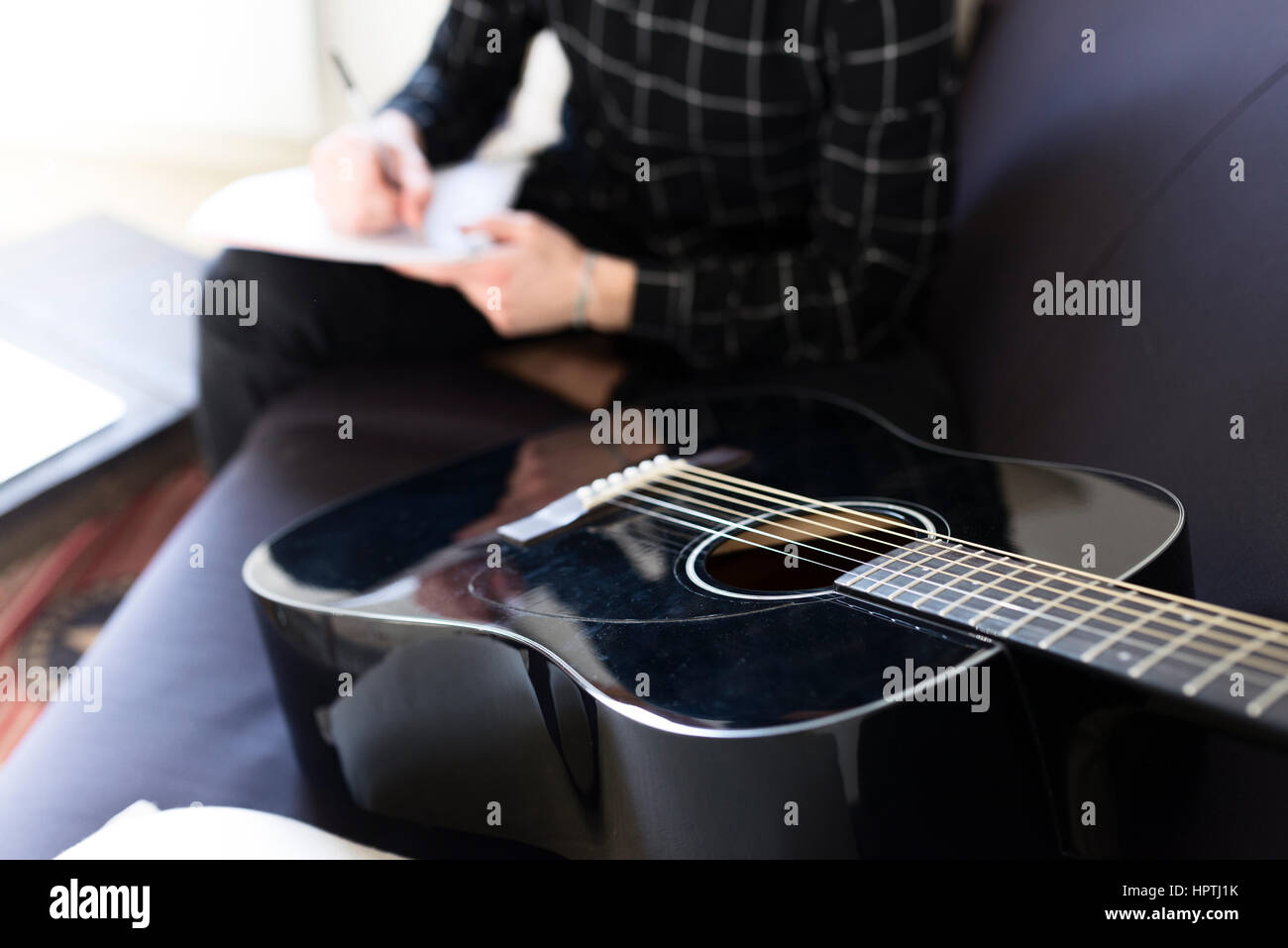 Guitar on couch and man taking notes Stock Photo