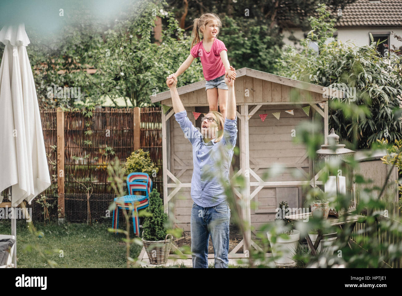 Father carrying daughter on shoulders in garden Stock Photo