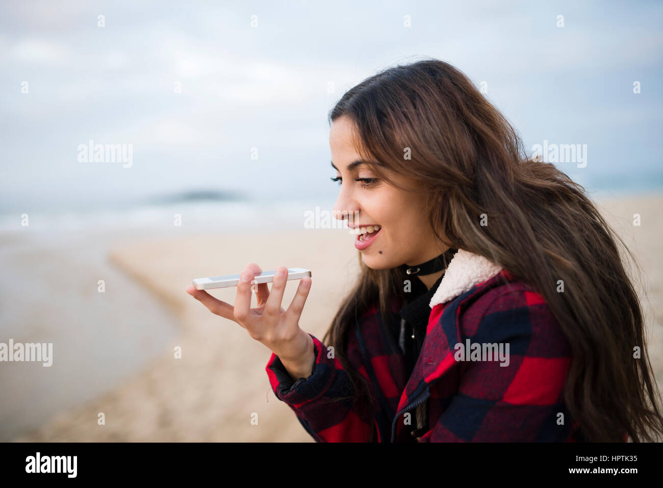 Portrait of young woman using smartphone on the beach Stock Photo