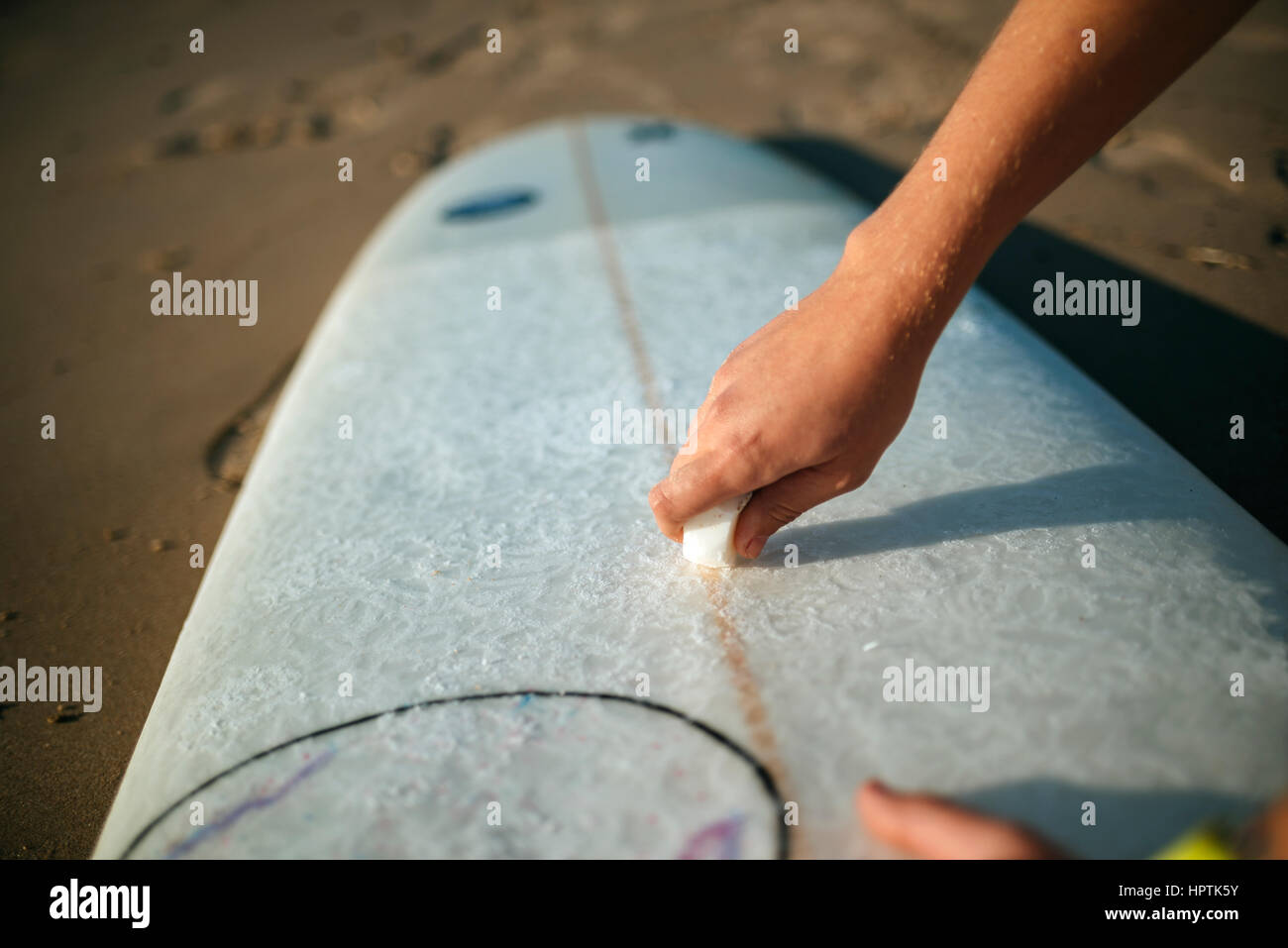 Woman's hand applying paraffin on  surfboard, close-up Stock Photo