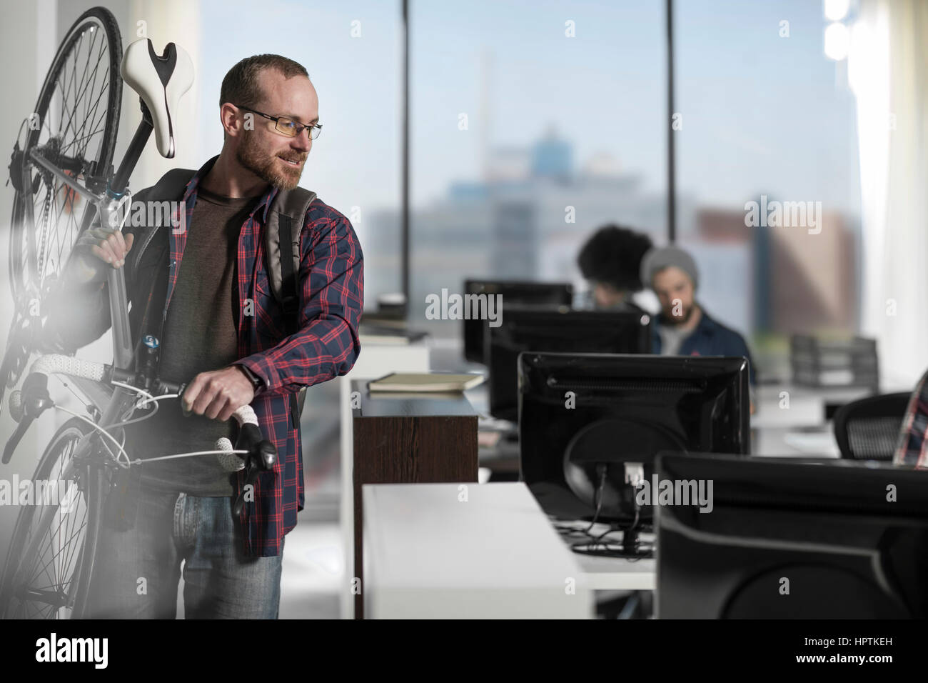 Casual man carrying bike in modern office Stock Photo Alamy