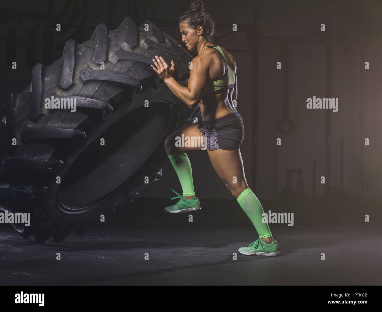 Young woman lifting up a tractor tyre Stock Photo