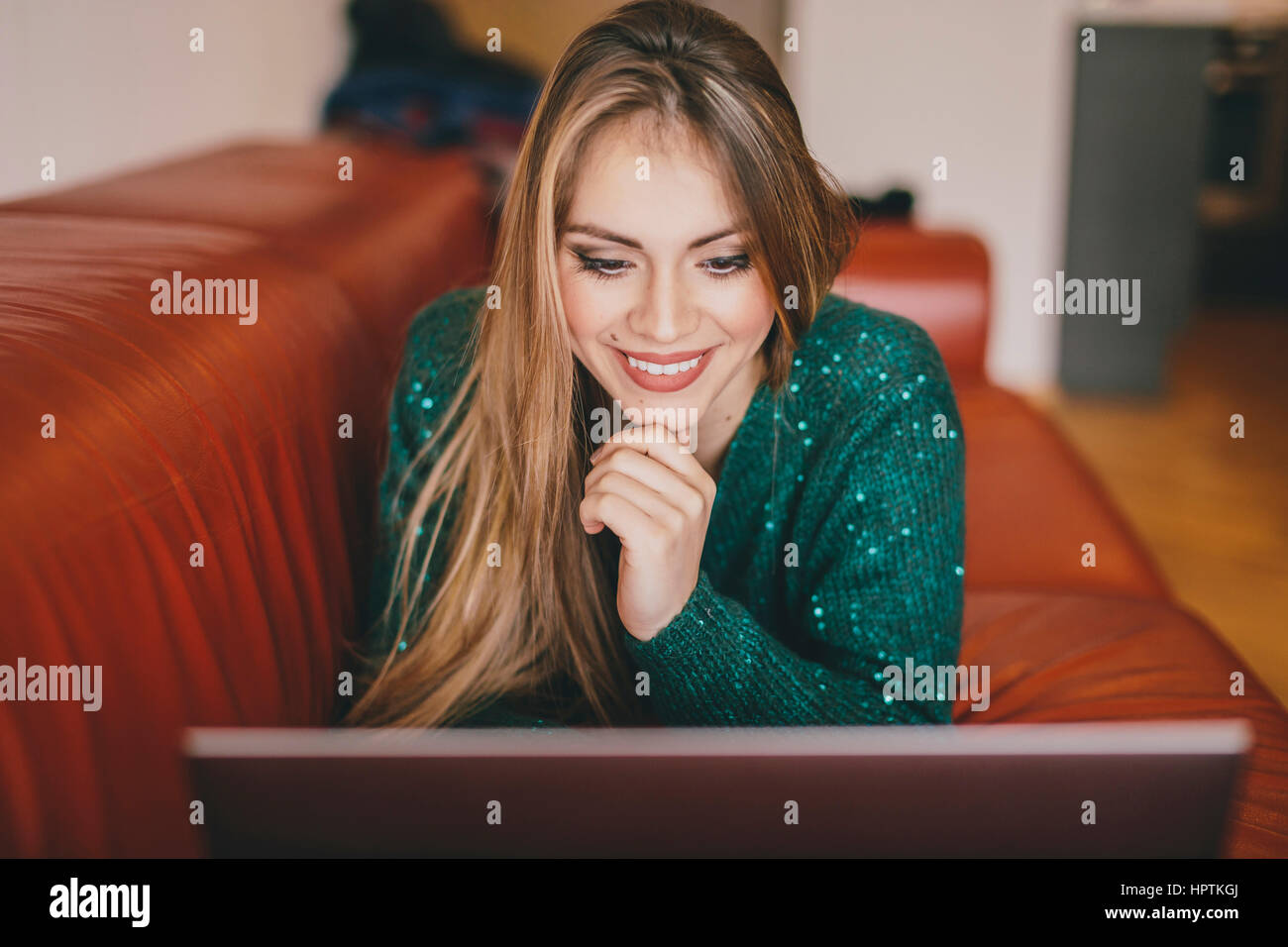 Young woman relaxing on the couch using laptop Stock Photo - Alamy