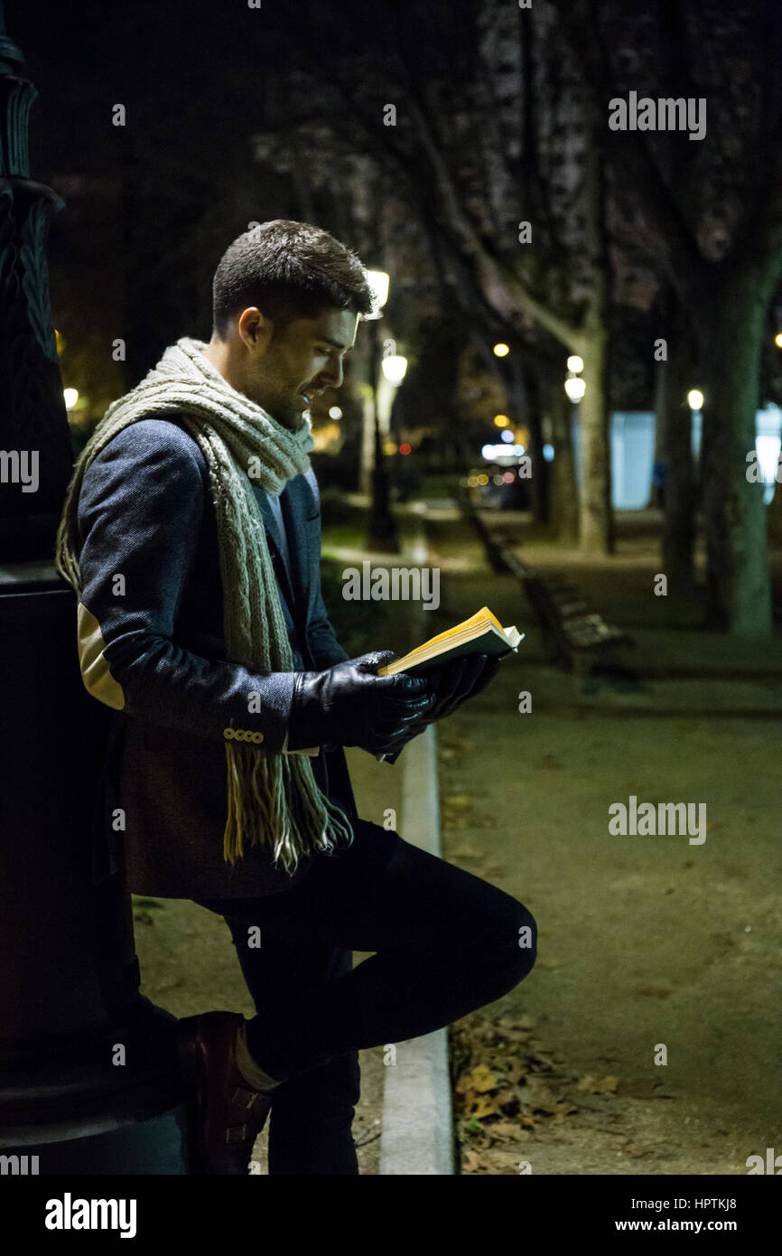 Man reading a book in a park at night Stock Photo