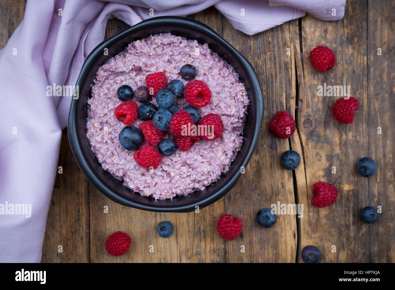 Bowl of overnight oats with blueberries and raspberries on wood Stock Photo