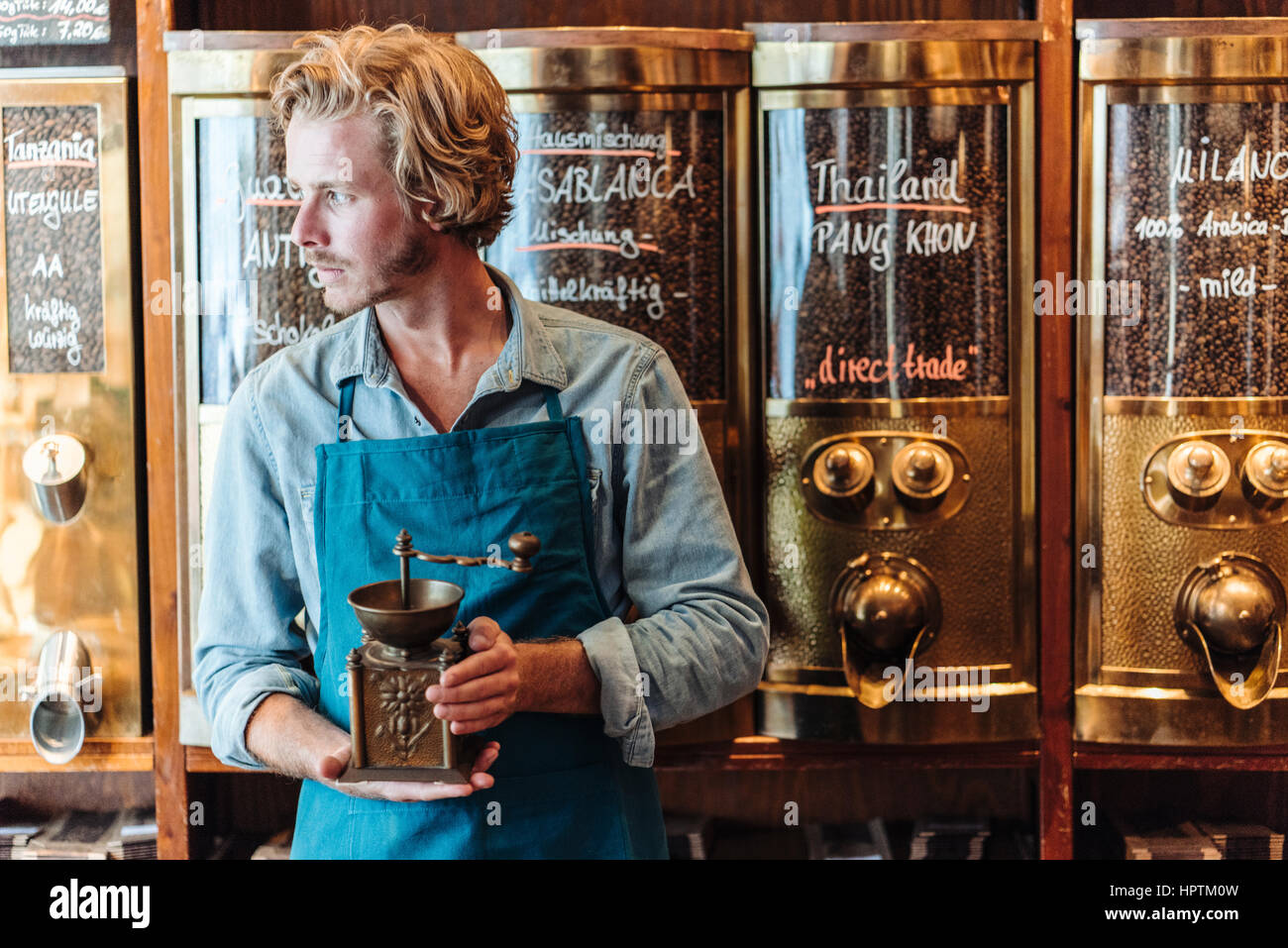 Coffee roaster in his shop holding oldfashioned coffee mill Stock