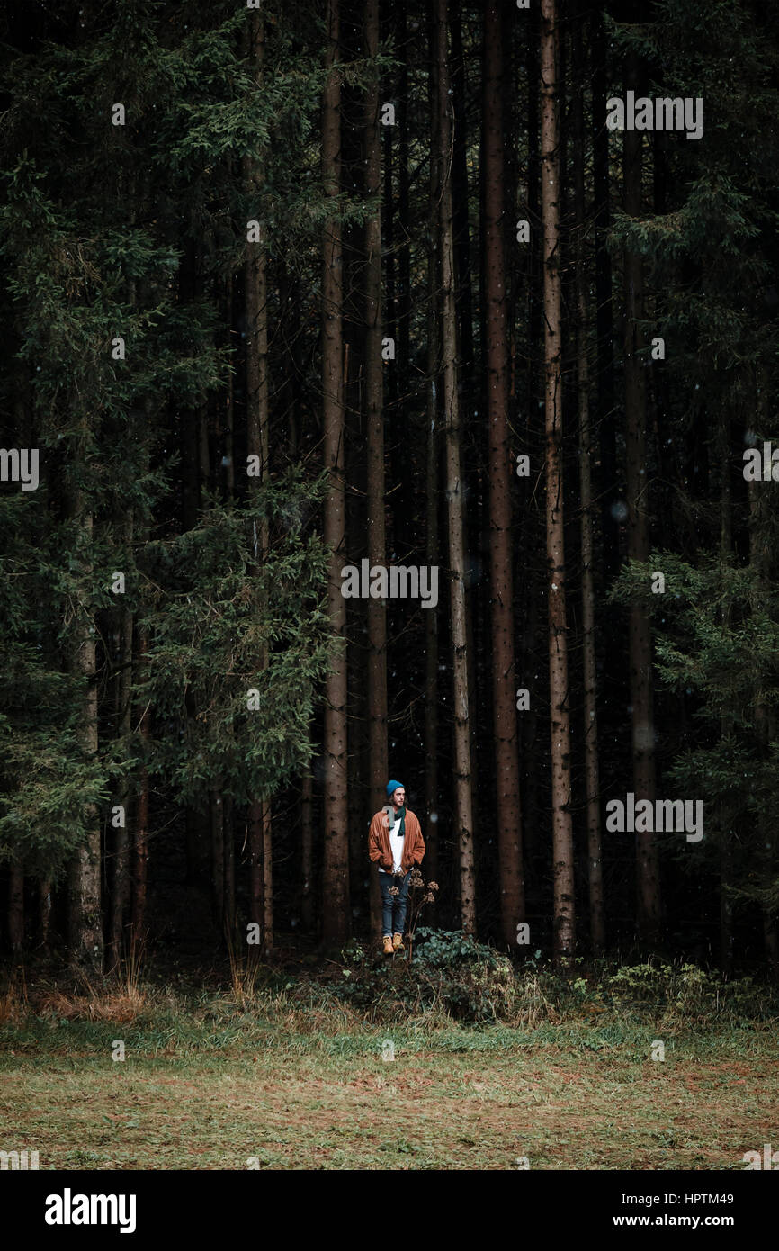 Young man standing in front of coniferous forest Stock Photo - Alamy