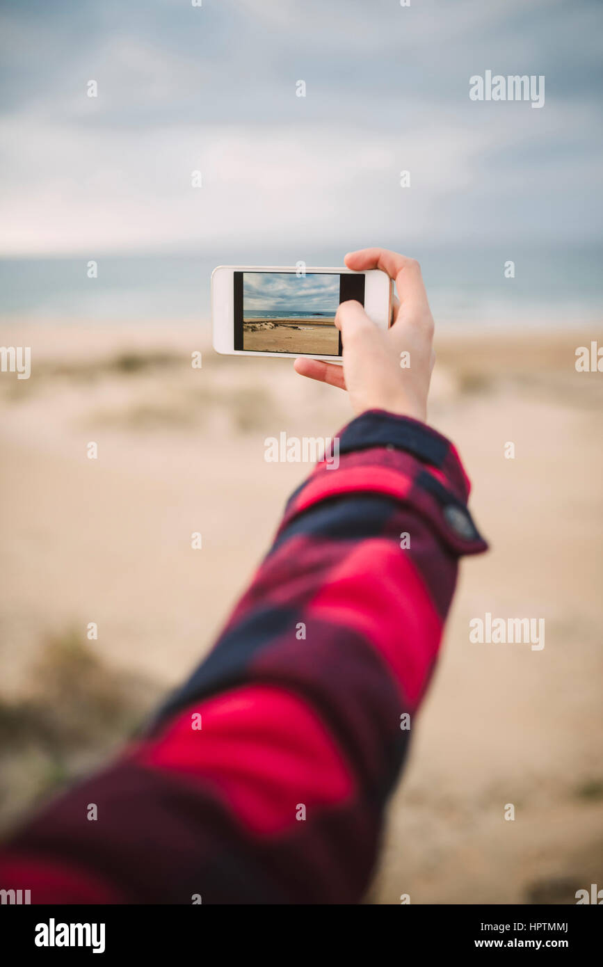 Woman's hand taking picture of the beach with smartphone Stock Photo