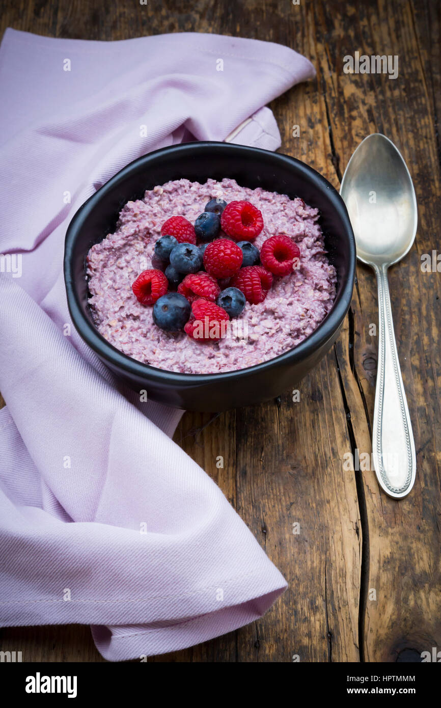 Bowl of overnight oats with blueberries and raspberries on wood Stock Photo