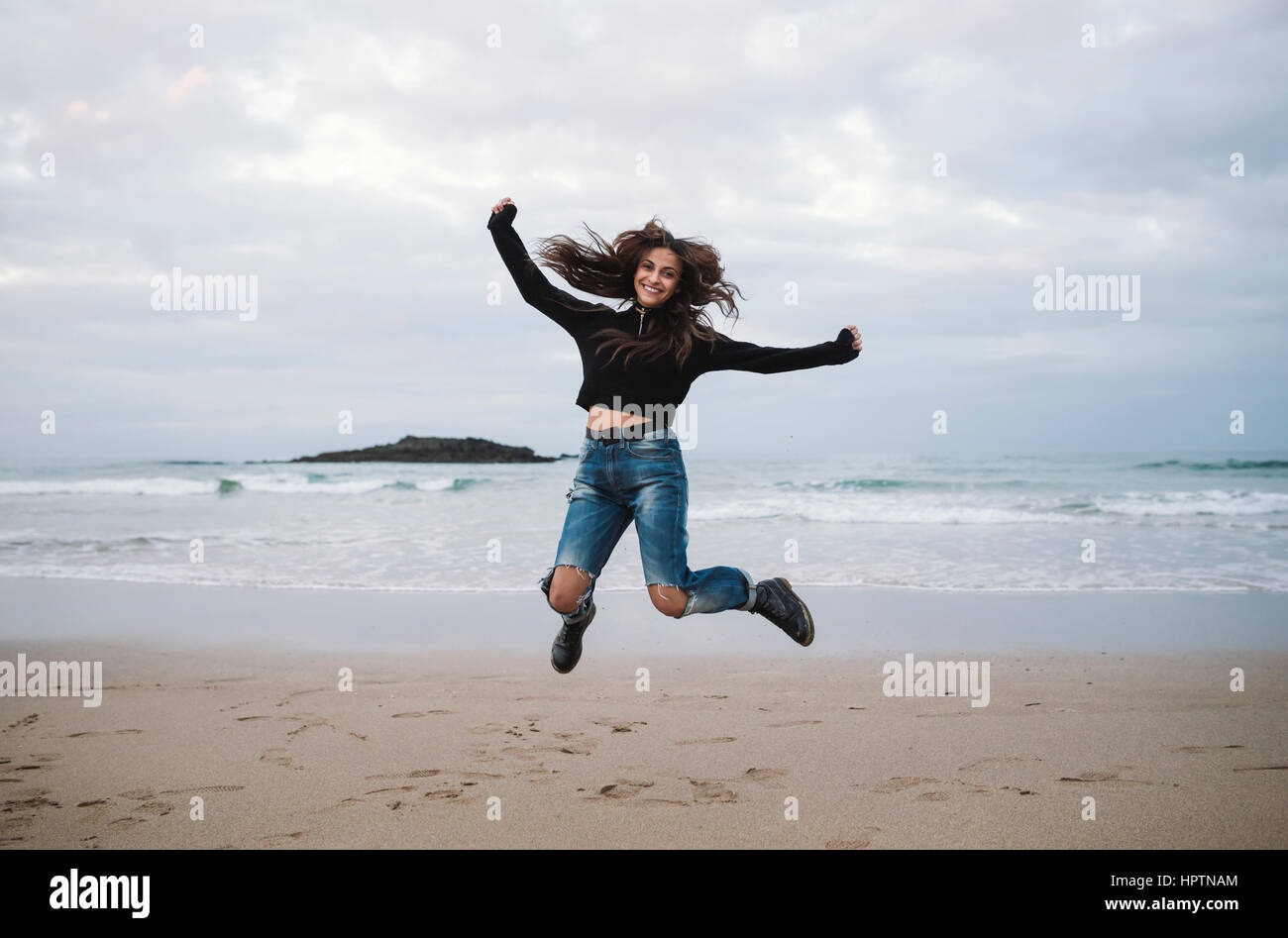 Happy woman jumping in the air on the beach Stock Photo
