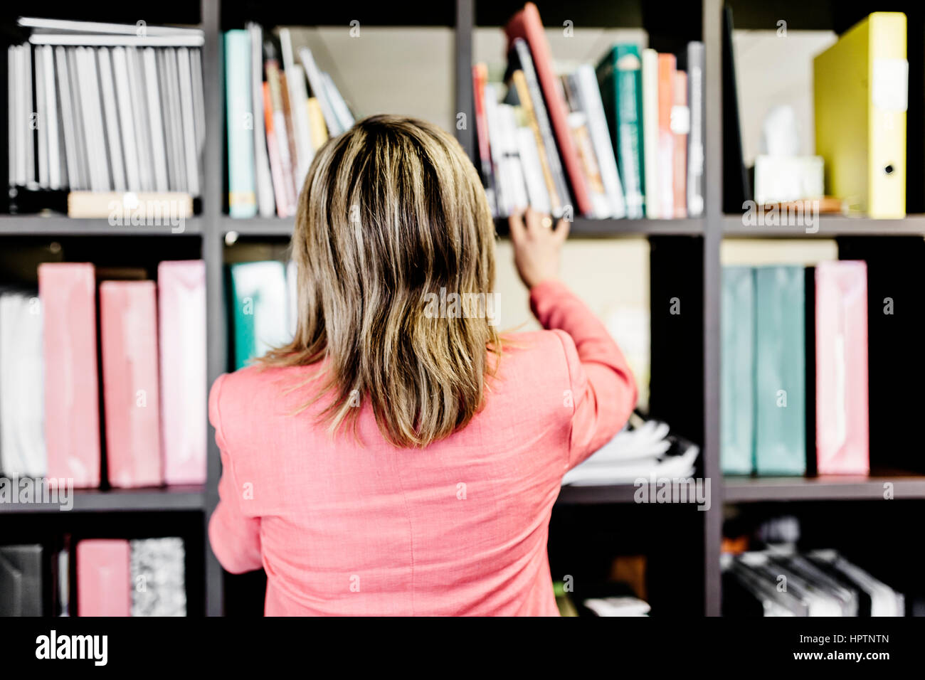 Rear view of businesswoman at bookshelf Stock Photo