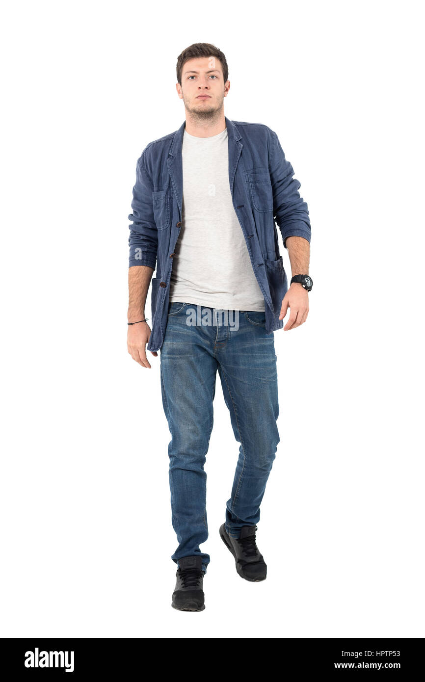 Young confident man in denim unbuttoned shirt and jeans walking towards ...