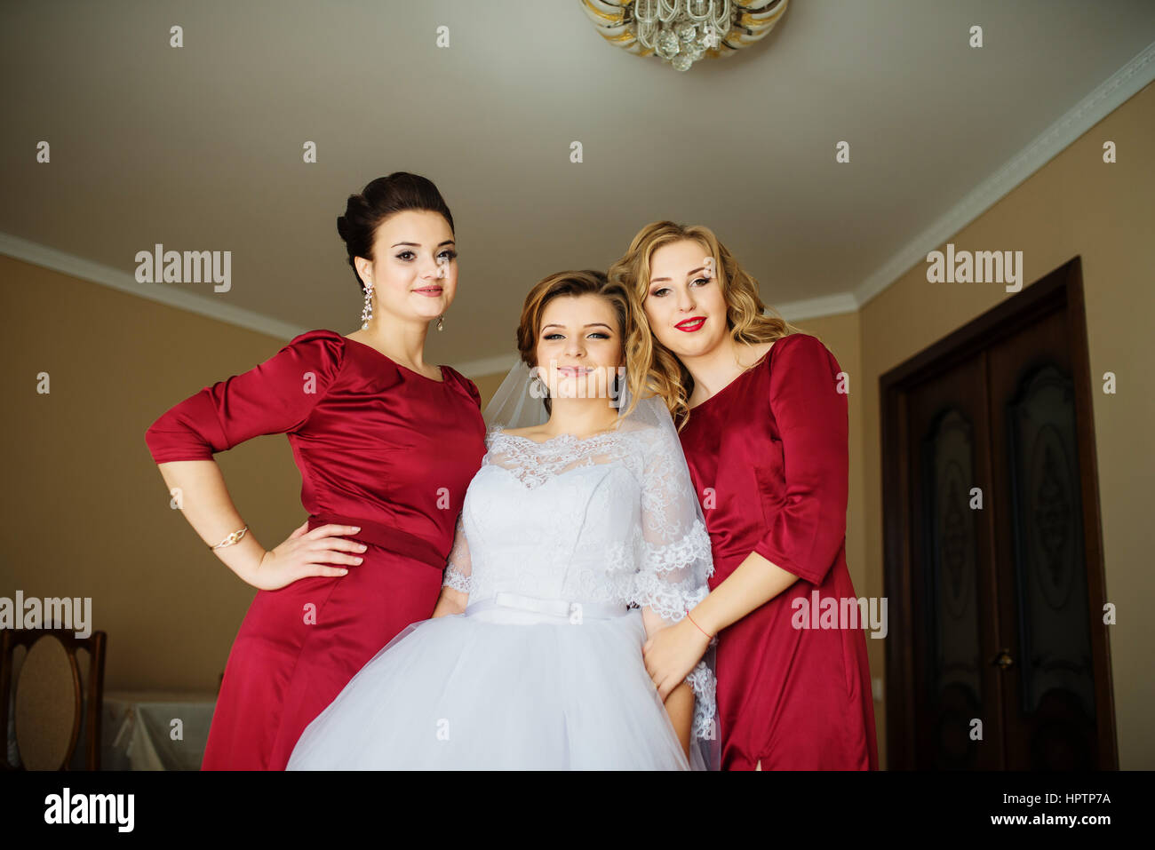 Cute blonde bride with bridesmaids posed on room at wedding morning day. Stock Photo