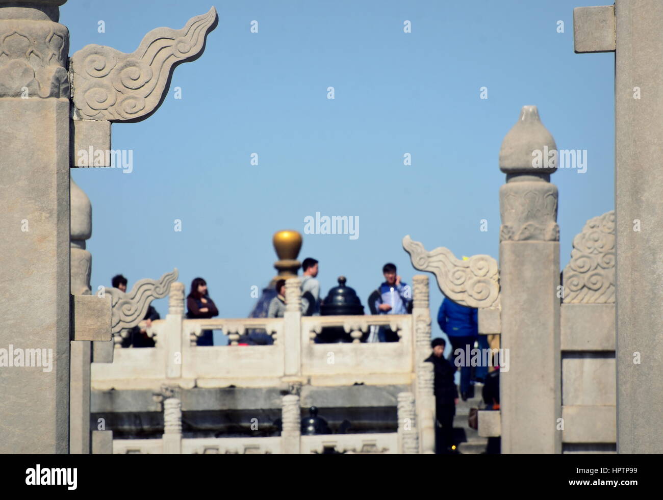 Successive portals and gates in traditional Chinese architecture leadinto the Temple of Heaven altar with Chinese visitors on its top - Beijing, China Stock Photo