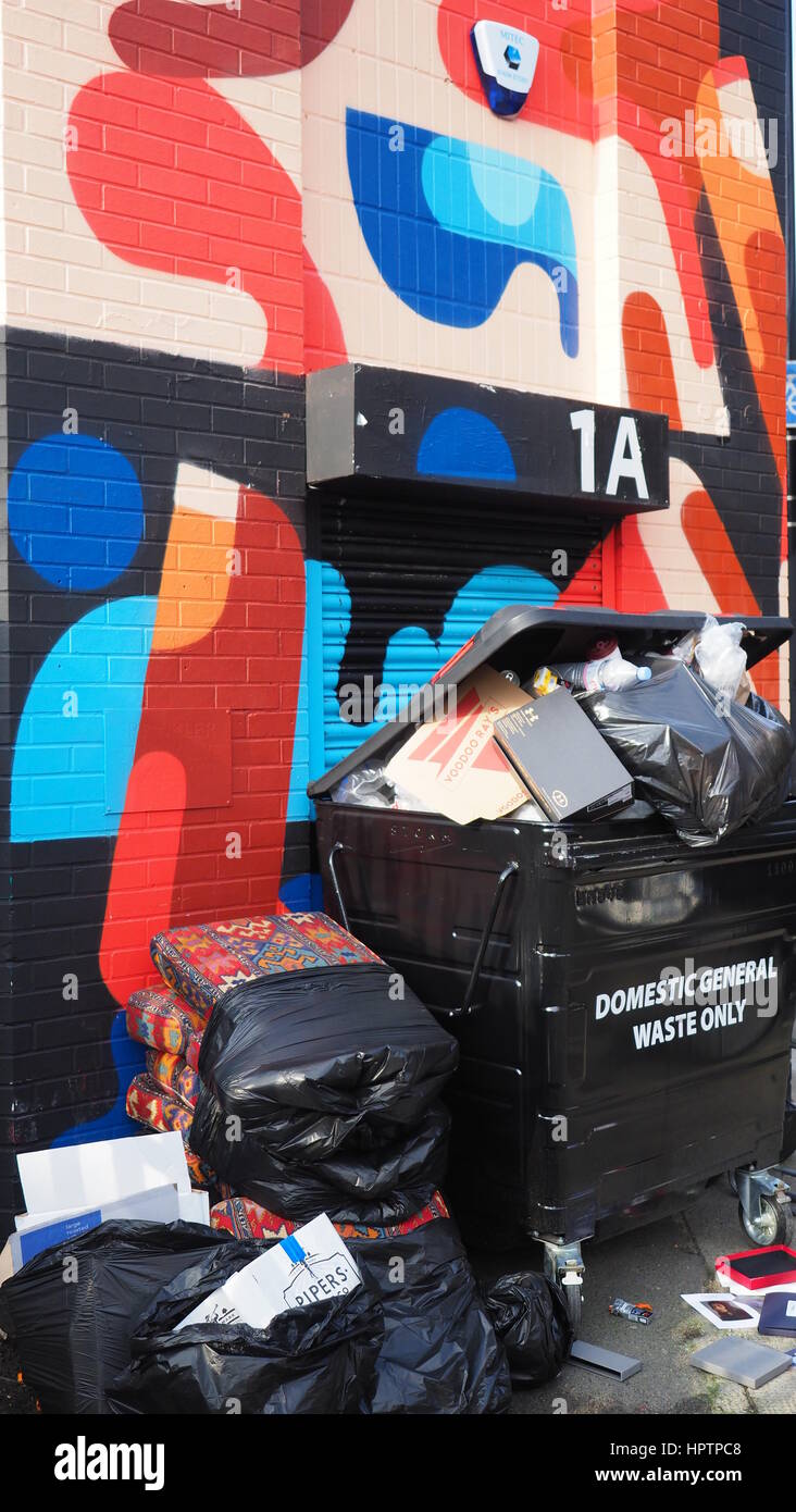 Rubbish piled against a street wall with graffiti Stock Photo