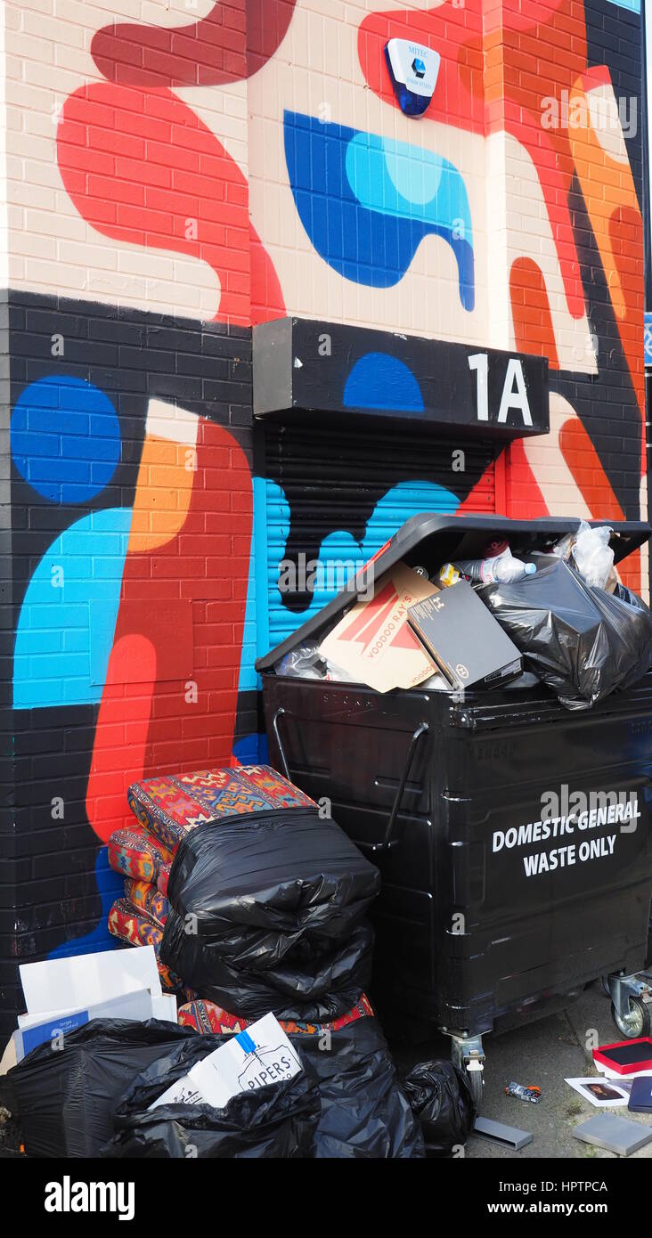 Rubbish piled against a street wall with graffiti Stock Photo