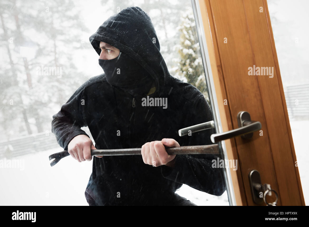 house robbery - robber trying open door with crowbar Stock Photo