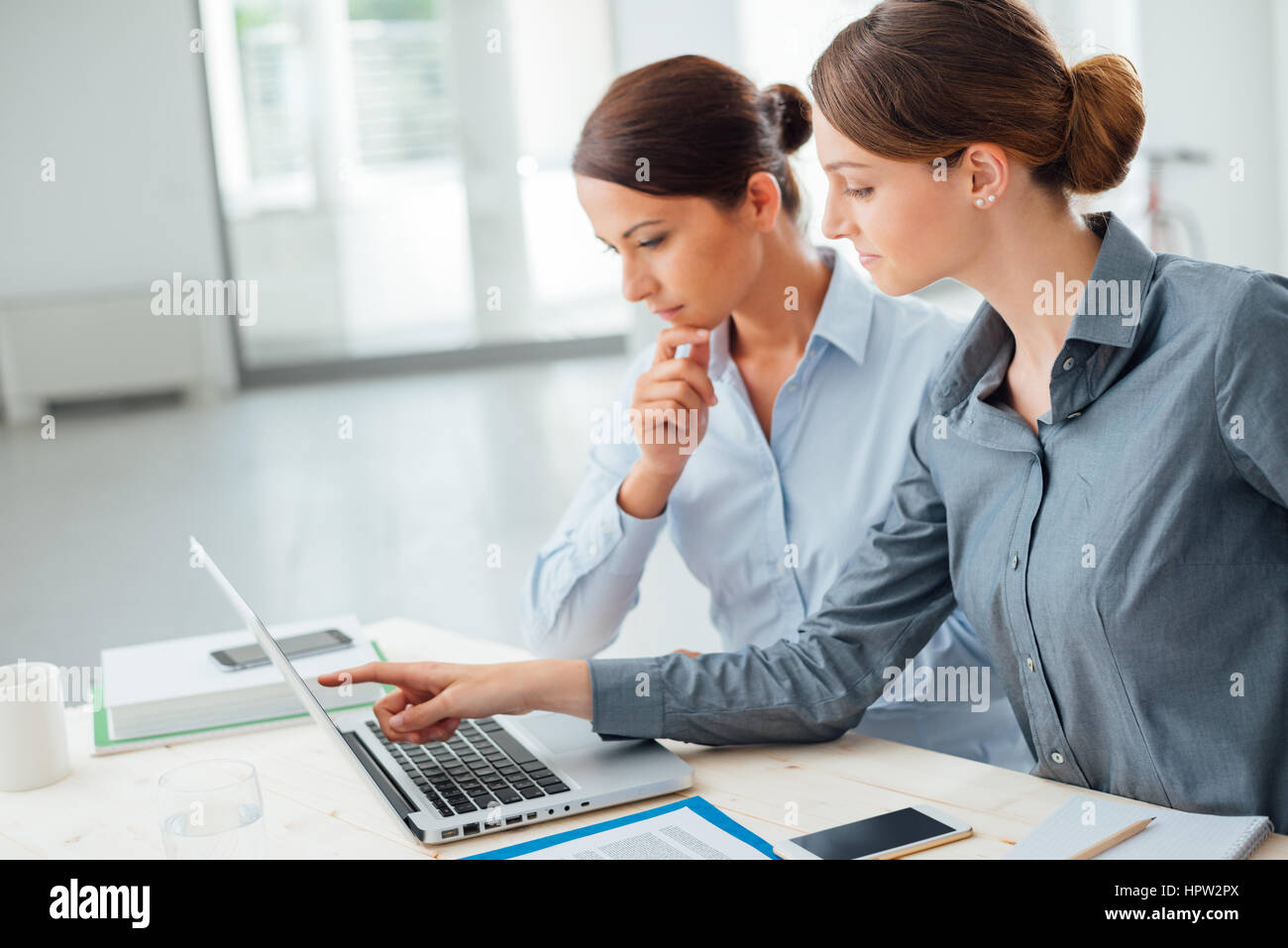Business women at office desk working together on a laptop, teamwork ...