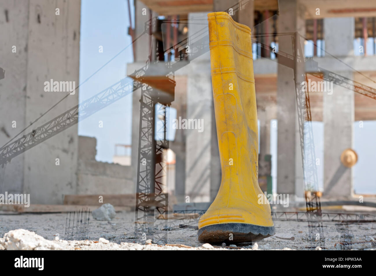 double exposure of a steel toed work boot and construction tower cranes Stock Photo