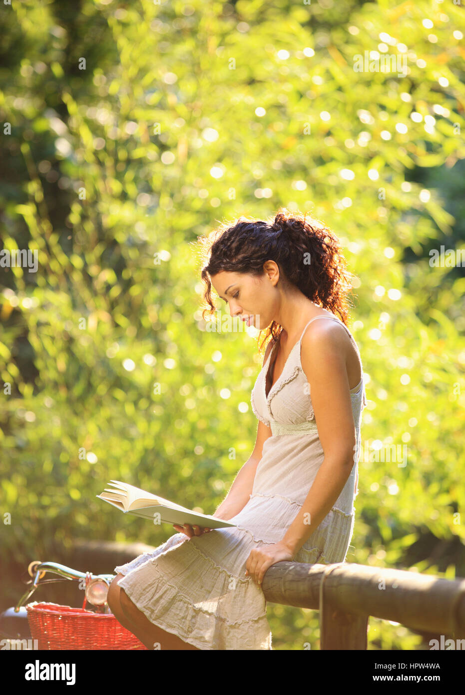 Young woman reading a book at a park Stock Photo - Alamy