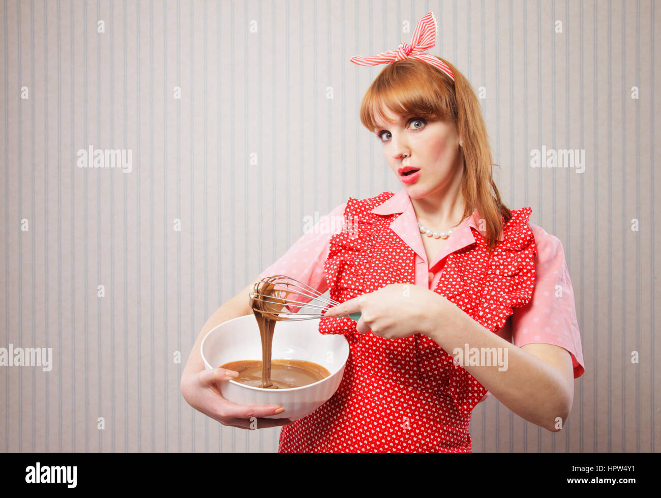 Stereotypical housewife, manual mixer and bowl, on wallpaper background Stock Photo