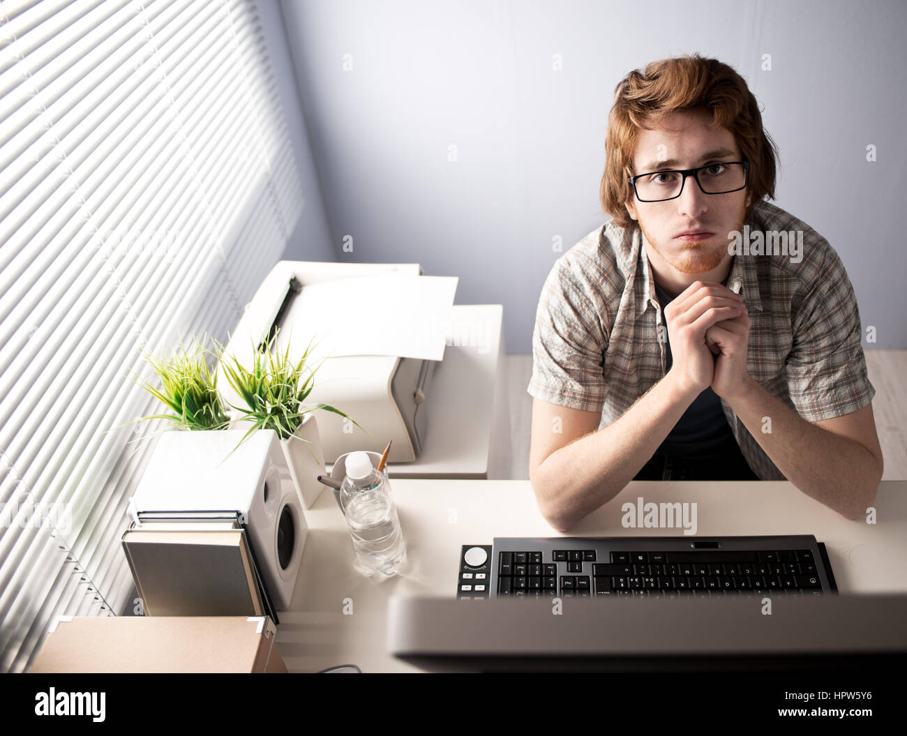 Young bored man at office with hands clasped. Stock Photo