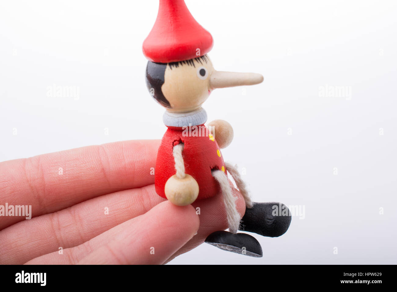 Wooden pinocchio doll in hand on a white background Stock Photo - Alamy