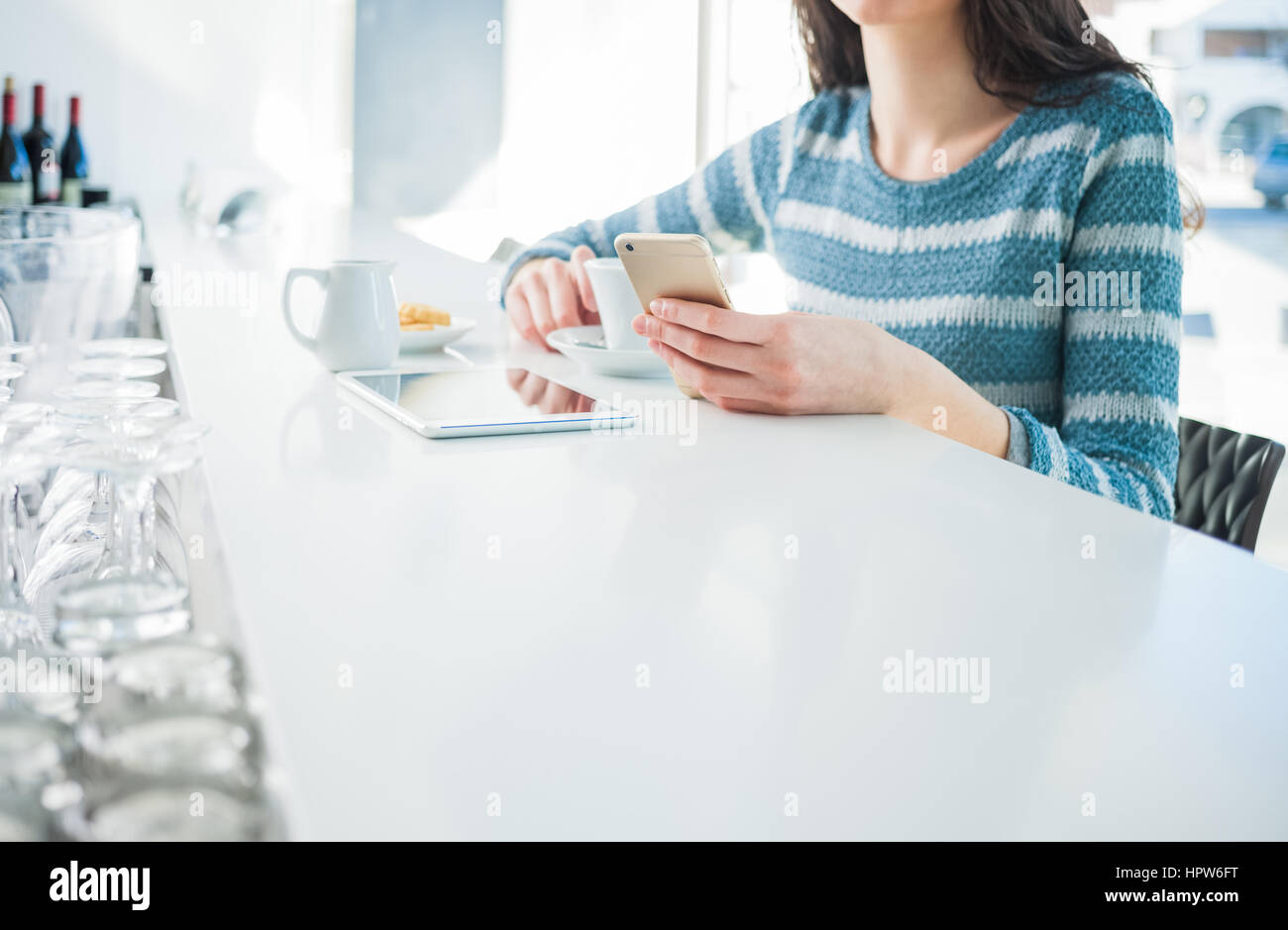 Woman at the bar sitting at the counter and using a mobile phone, hands detail Stock Photo