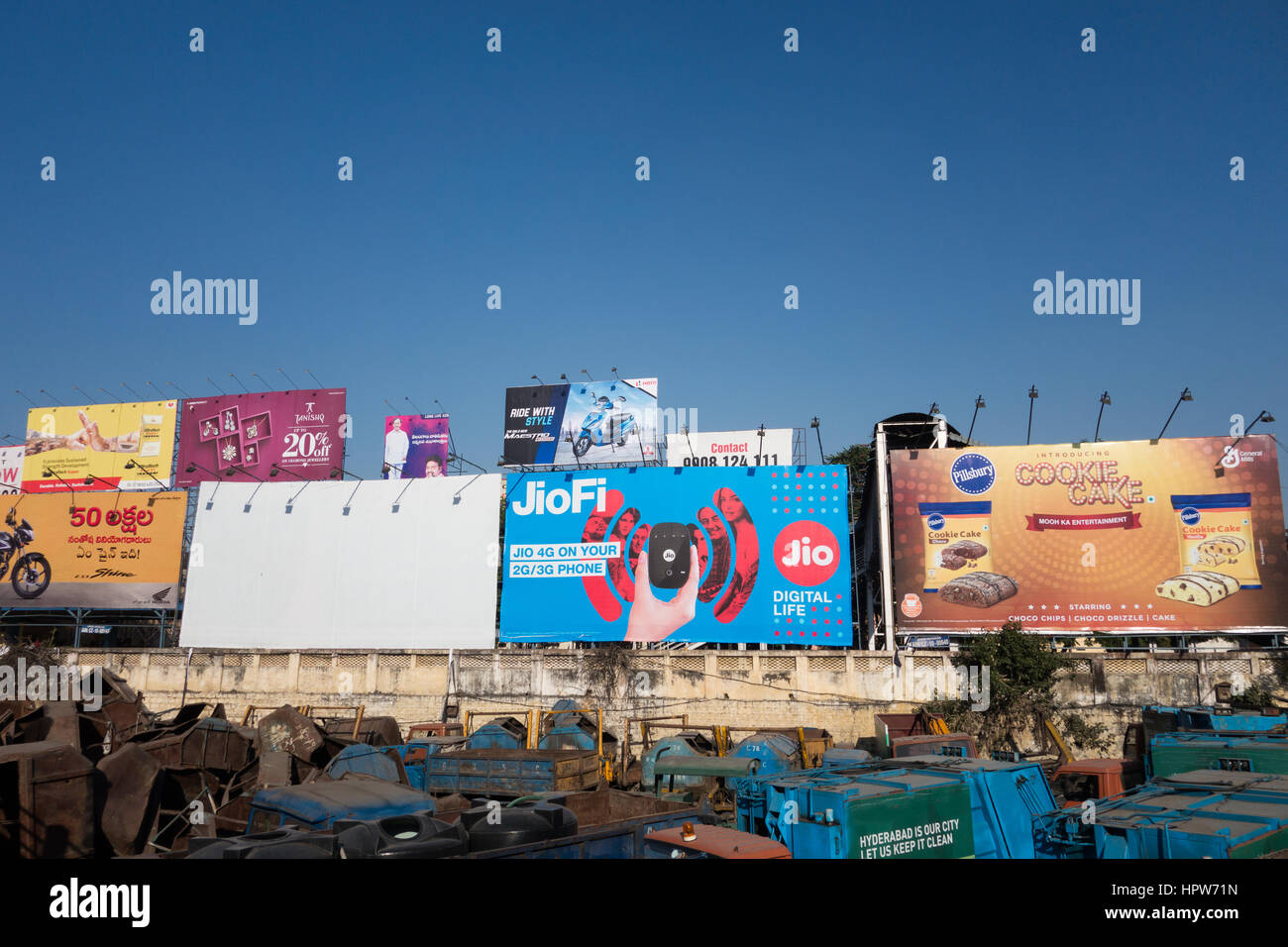 HYDERABAD, INDIA - FEBRUARY 21,2017 Hoarding and billboards dot the sky advertisements of various companies near a garbage truck dump yard in Hyderaba Stock Photo