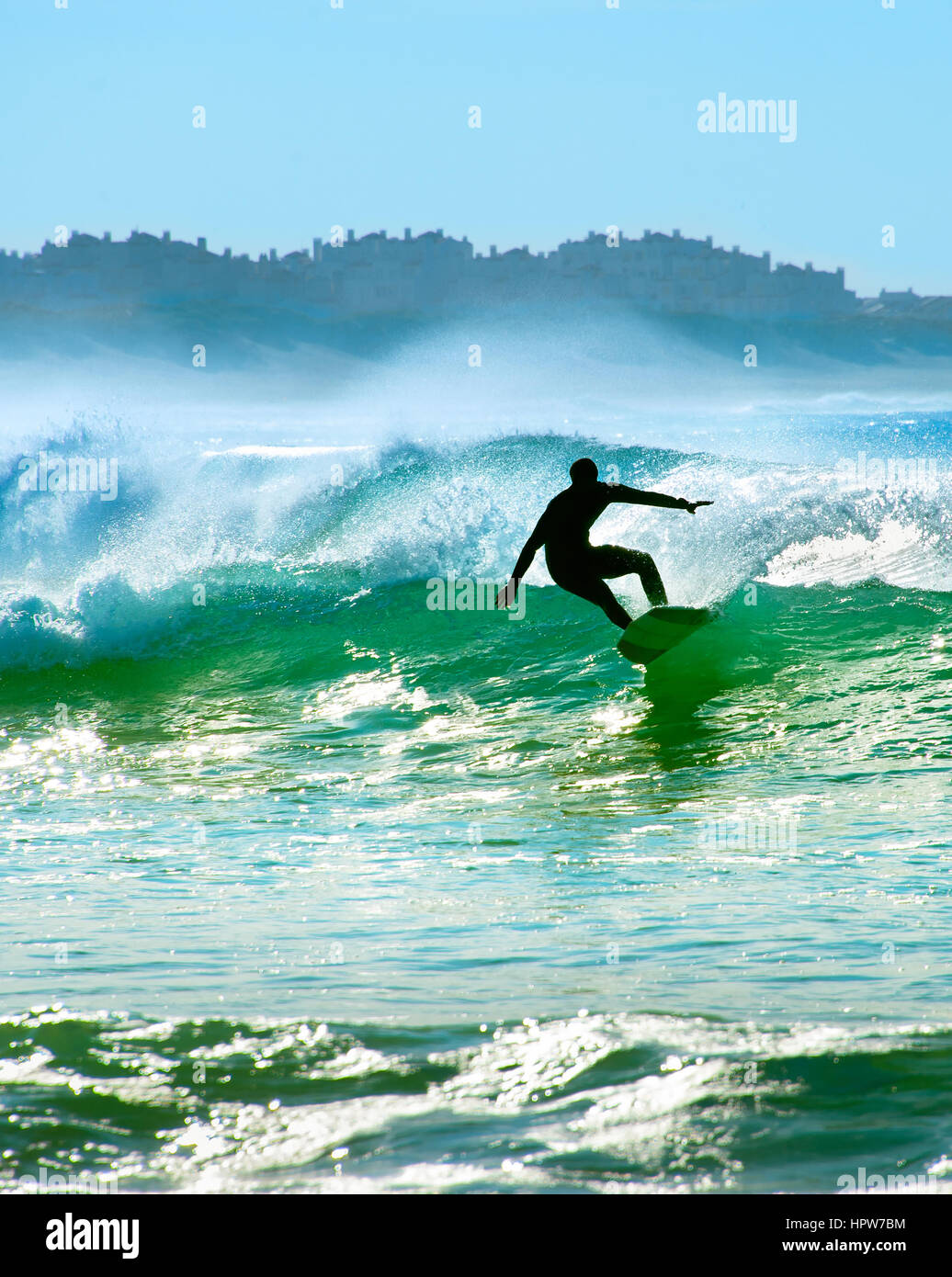 Silhouette of a surfer riding a wave in the ocean Stock Photo