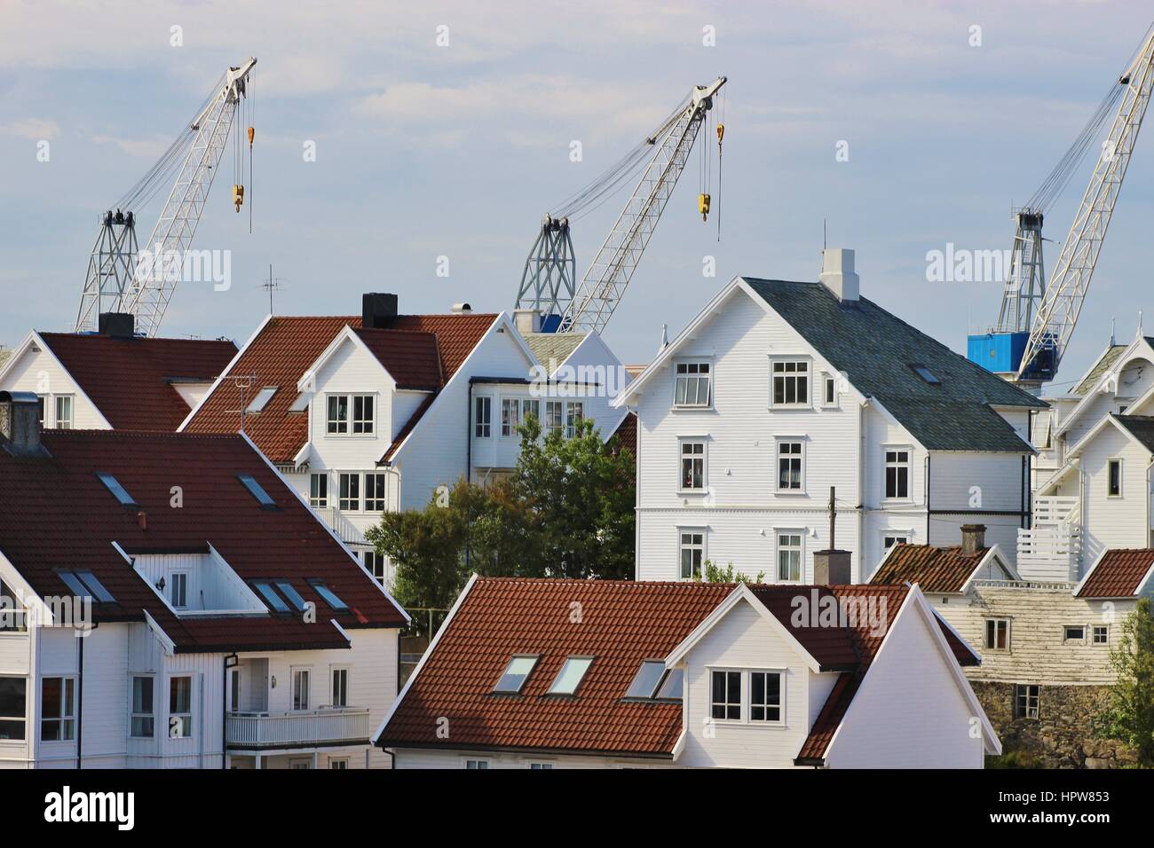 Houses on the Island Risoy, part of the town Haugesund, with cranes of a shipyard in the background. West coast of Norway, Scandinavia, Europe. Stock Photo