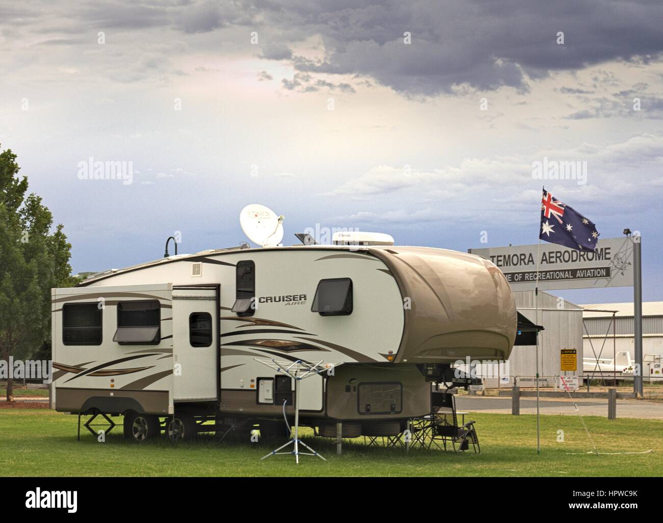 Large cruiser caravan parked in Temora campground, beside the aerodrome, Australian flag flying in the background. Stock Photo