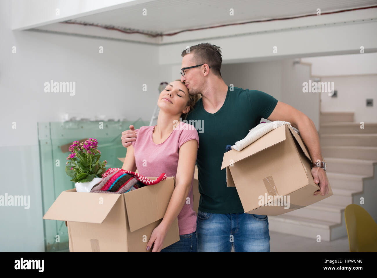 Happy young couple unpacking or packing boxes and moving into a new ...