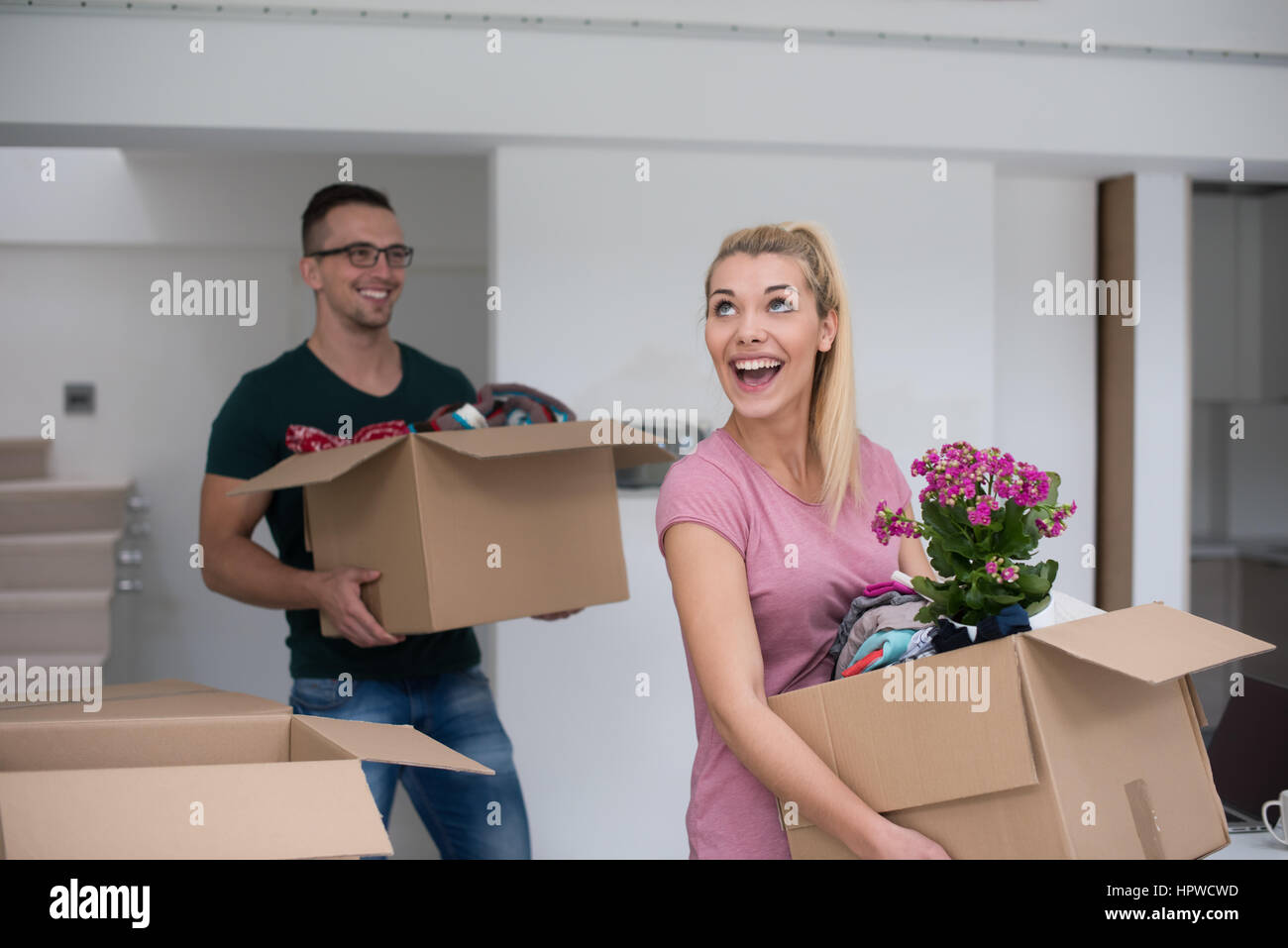 Happy young couple unpacking or packing boxes and moving into a new ...