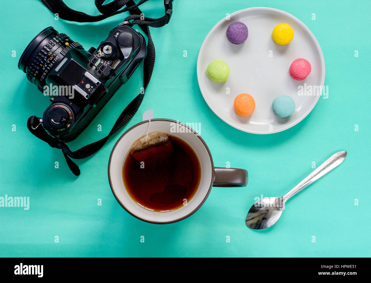 colorful french macaron,cup of tea and SLR camera on green background
